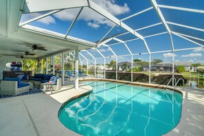 Una piscina techada con techo de vidrio, mobiliario exterior azul y vistas del vecindario circundante.