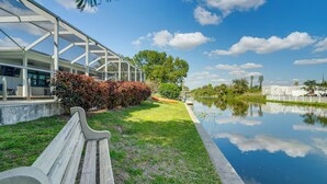 A park with a bench, a glass greenhouse, and a calm water body. - Canal-Front Gem w/ Hot Tub, Foosball in Cape Coral (Cape Coral)