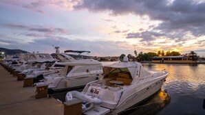 A marina with several boats docked, a clear sky, and a sunset in the background.