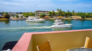 A marina with yachts docked, a view of the water, and a building with a red roof in the background.