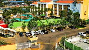 A hotel with a swimming pool, multiple parking spaces, and a view of the ocean.