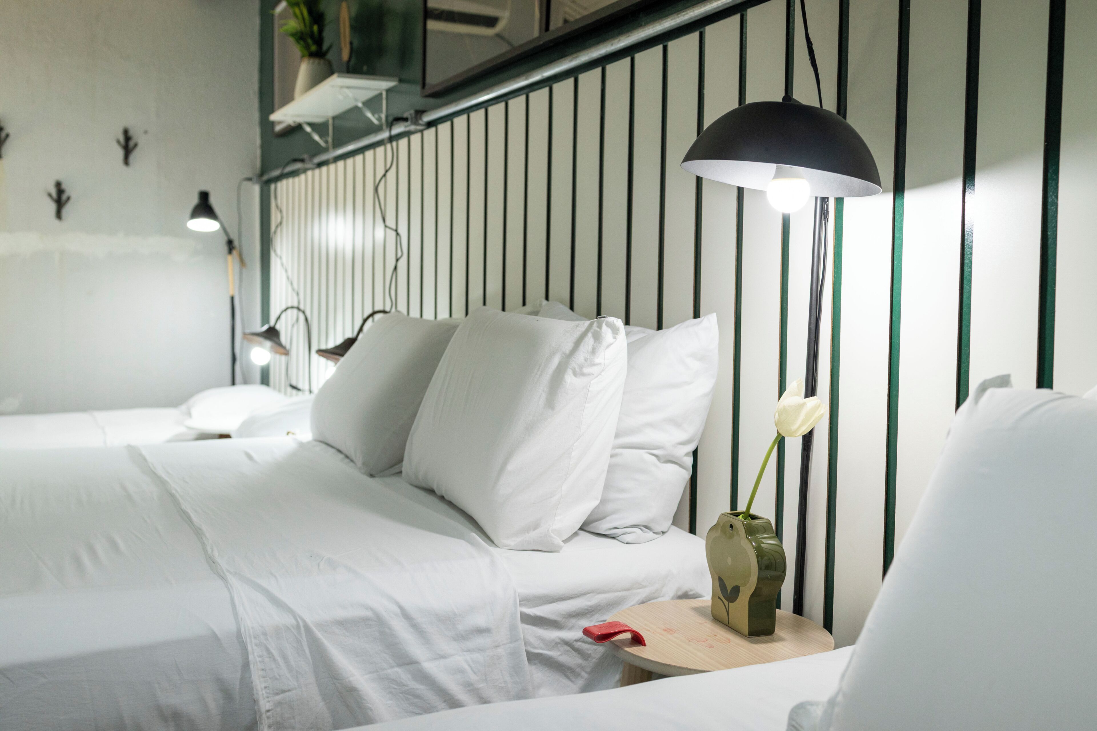 Una camera da letto moderna con un letto, abat-jour, un vaso con un fiore e uno scaffale a parete.