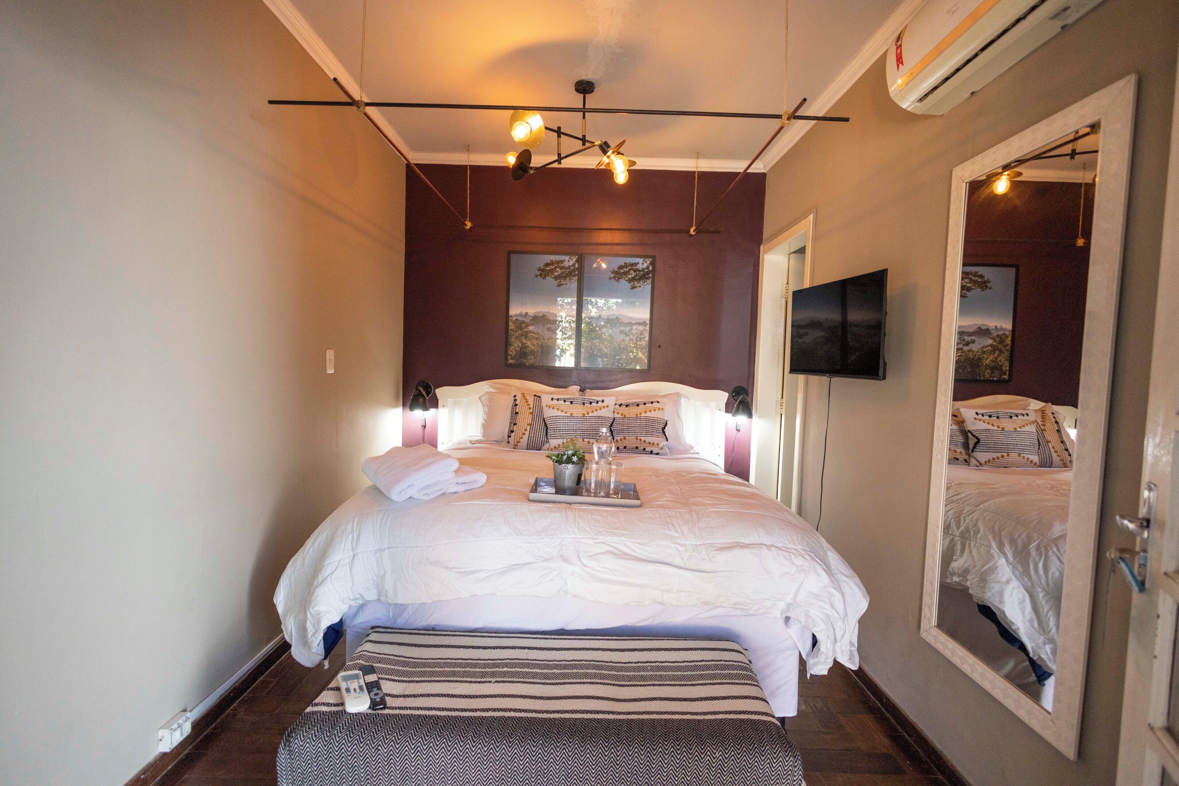 A neatly made bed with a tray, a television on the wall, and a large mirror.