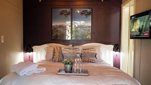 A neatly made bed with a tray of towels, a small plant, and glasses on a tray. - Happiness House Hospedagem (Cuiaba)