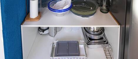 A kitchen with a white cabinet containing dishes, glasses, and a tea kettle.