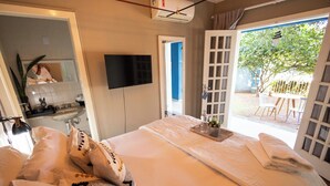 A hotel room with a bed, a TV, a bathroom, and a view of the outside. - Happiness House Hospedagem (Cuiaba)