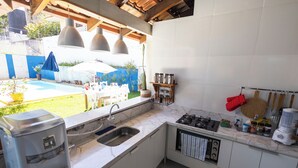 A kitchen with a built-in oven, a coffee maker, and a sink. - Happiness House Hospedagem (Cuiaba)