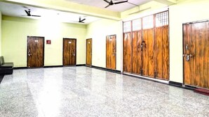 A hallway with wooden doors, ceiling fans, and a tiled floor. - Hotel Radhey inn (Kanpur)