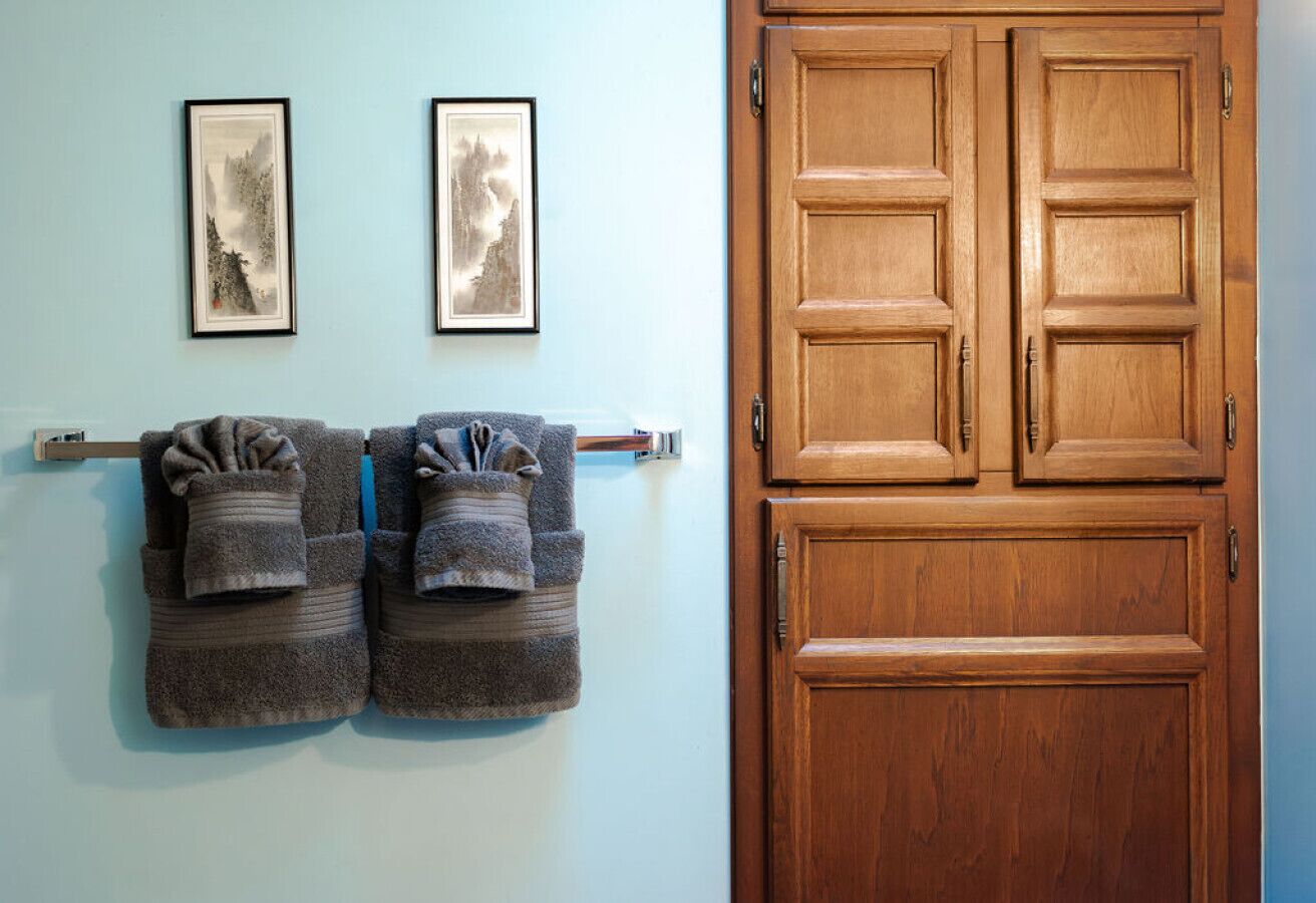 A room with a wooden door, two framed artworks on the wall, and two towels hanging on a towel rack.