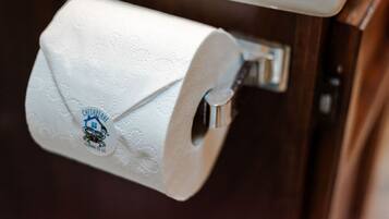 A toilet paper roll mounted on a metal holder attached to a wall.