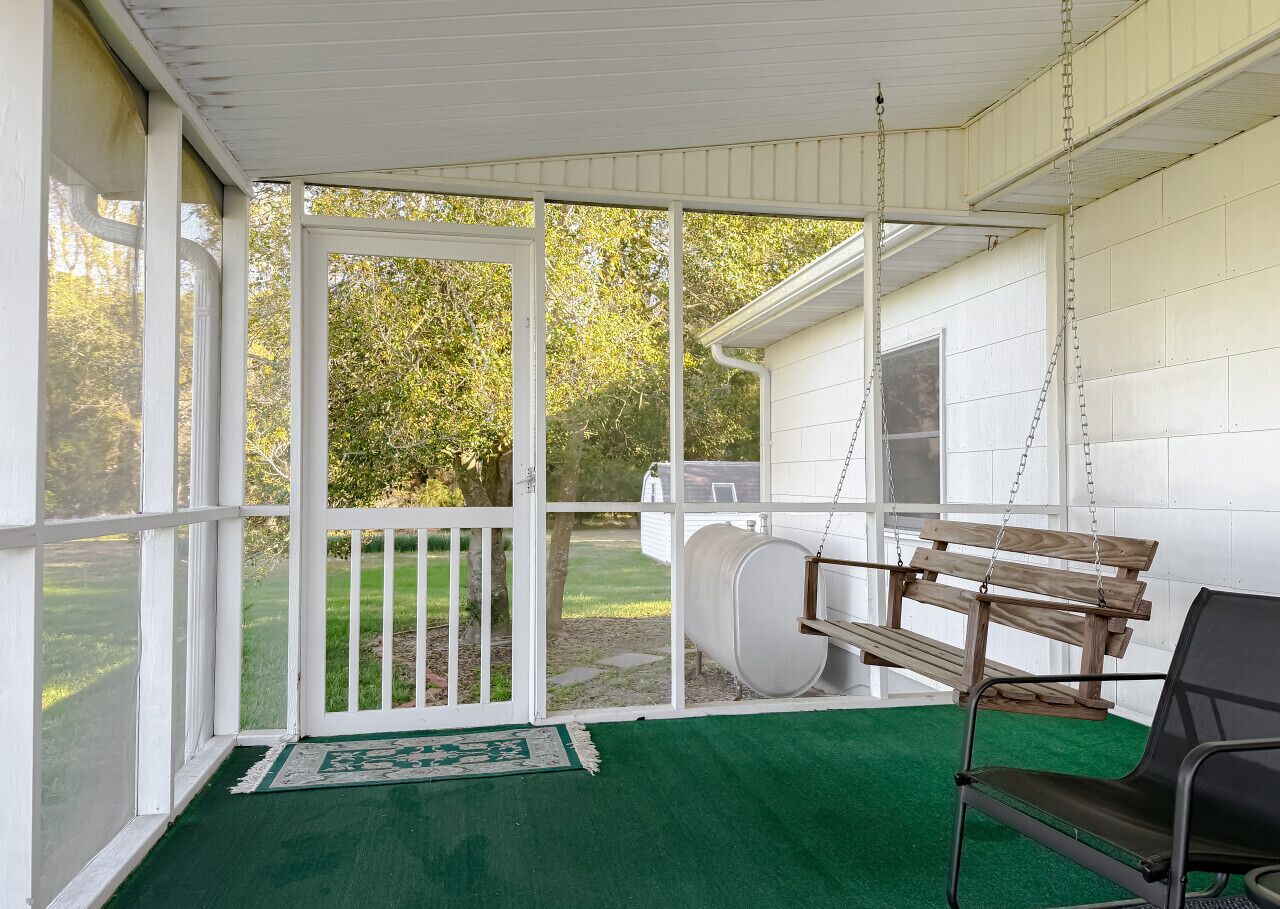 A covered porch with a swing, a bench, and a chair.