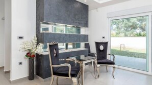 A modern kitchen with a dark backsplash, a glass-top table, and two chairs. - Villa Fažana (Fažana)