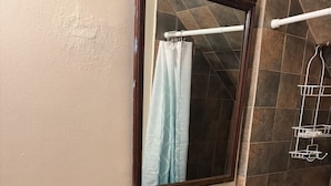 Casa de banho com pia branca, espelho, porta-toalhas e zona de duche.