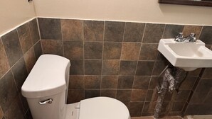 A bathroom with a toilet, a roll of toilet paper, and a sink. - One bedroom  in United States of America, New York (New York)