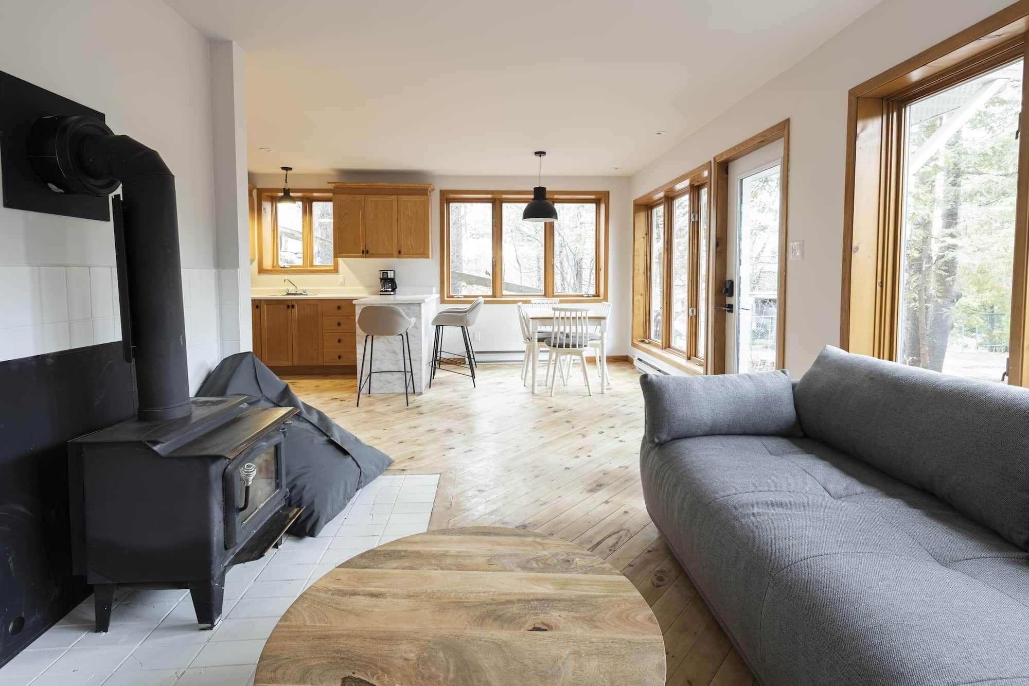 Un salon moderne avec un canapé, une cheminée et un coin repas baigné de lumière naturelle.