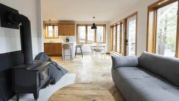 Un salon moderne avec un canapé, une cheminée et un coin repas baigné de lumière naturelle.
