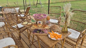 An outdoor dining area with wicker chairs and a wooden table set with food and drinks. - Villa Blanche Domaine de la Tapie de Bouchet - in the Camargue (Arles)