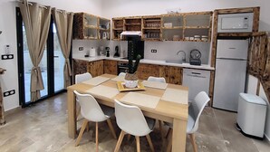 A compact kitchen with wooden cabinets, a dining table with chairs, and a built-in microwave. - Villa Blanche Domaine de la Tapie de Bouchet - in the Camargue (Arles)