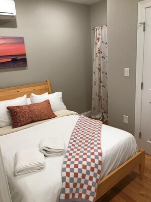 A neatly made bed with white linens, a checkered blanket, and a floral-patterned curtain. - Lux 1st floor 3brm/1bath North End (Boston)
