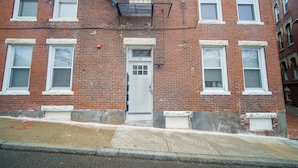 A red brick building with a white door, numbered 19, and multiple windows.