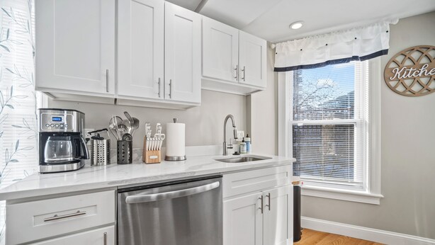 A modern kitchen with white cabinets, stainless steel appliances, and a built-in dishwasher.