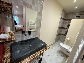 A modern bathroom with a black sink, a mirror, a towel rack, and a shower area. - Villa Framboise Domaine de la tapie de Bouchet - en Carmargue (Arles)