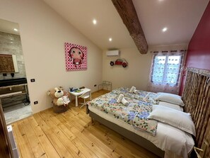 A cozy bedroom with a wooden floor, a bed with floral bedding, a teddy bear, a small table, and a wall with a cartoon character. - Villa Framboise Domaine de la tapie de Bouchet - en Carmargue (Arles)