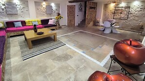 A modern living room with a wooden ceiling, a sofa with colorful cushions, a coffee table, and a unique orange sculpture.