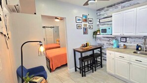 A compact living space with a kitchenette, a bed, a small dining area, and a bathroom.