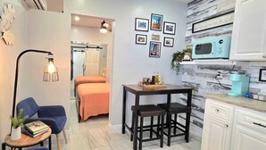 A compact kitchen with a microwave, a coffee machine, and a small dining table with stools.