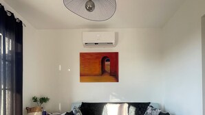 A living room with a light blue sofa, a round woven rug, and a modern pendant light. - Gite for 2, in the countryside, 15 minutes from the medieval town of Carcassonne (Verzeille)