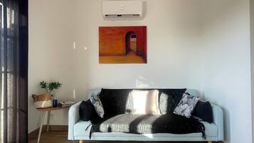 Ein Wohnzimmer mit einem hellblauen Sofa, einem runden gewebten Teppich und einer modernen Pendelleuchte.
