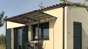A modern building with a covered patio, large windows, and a door. - Gite for 2, in the countryside, 15 minutes from the medieval town of Carcassonne (Verzeille)