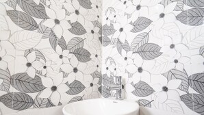A bathroom with a white sink, grey and white patterned tiles, and a grey floor.