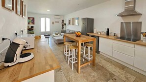 Eine moderne Küche mit einem Holztisch, Barhocker, einem eingebauten Backofen und einer Edelstahl-Dunstabzugshaube.