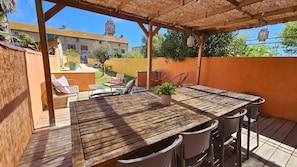 Une table en bois avec des chaises, une plante en pot et une structure de pergola.