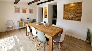 Ein Essbereich mit Holztisch und -stühlen, einem hellblauen Schrank und einer Ziegelwand mit einem Traumfänger.