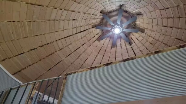 Une pièce dotée d’un plafond en pente, d’un luminaire central et d’un escalier en métal.