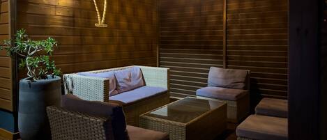 A cozy lounge area with wicker furniture, a potted plant, and a decorative wall hanging.