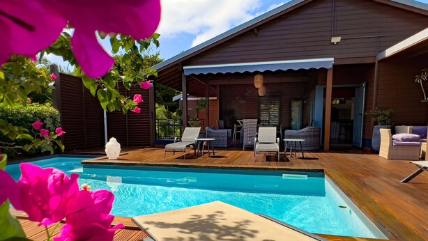 Une piscine avec des chaises longues et un patio couvert.