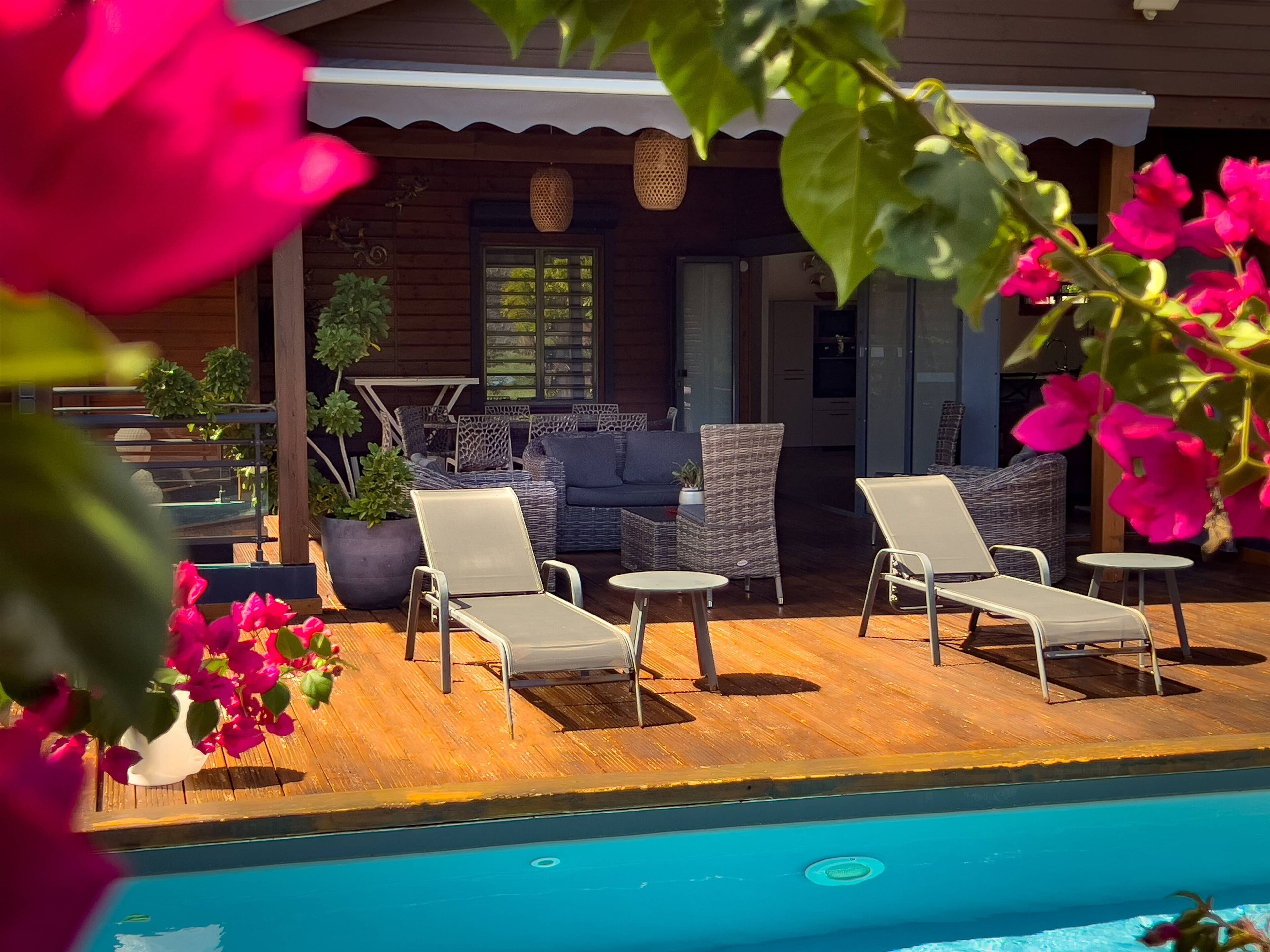 Uma área à beira da piscina com espreguiçadeiras e um deck de madeira.