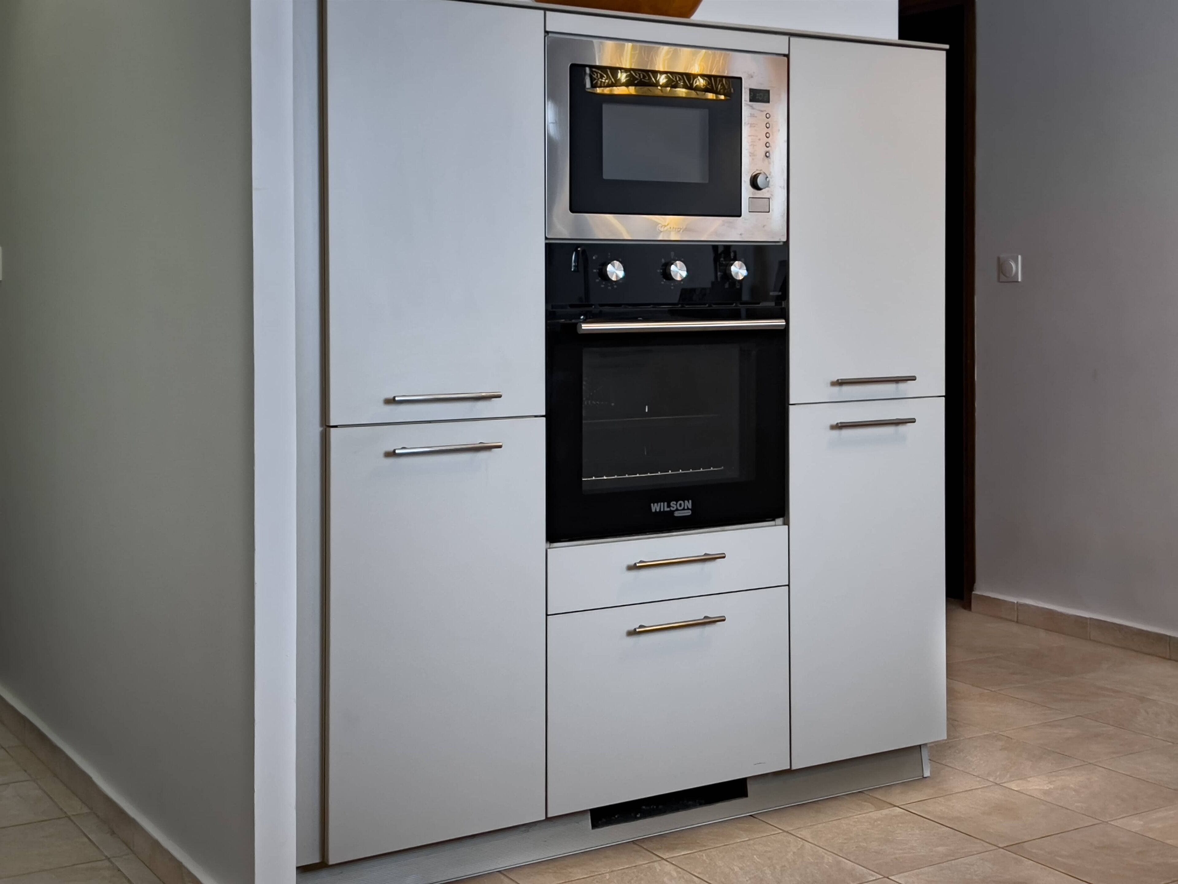 Eine Küche mit integriertem Mikrowellenherd, Backofen und zwei Schubladen.