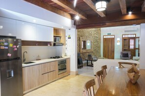 A modern kitchen with wooden cabinets, stainless steel appliances, and a dining area with a wooden table and chairs. - Espectacular La Casita Cartagena (Cartagena)