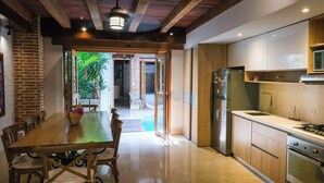 A modern kitchen with wooden cabinets, a stainless steel refrigerator, and a dining area with a wooden table and chairs. - Espectacular La Casita Cartagena (Cartagena)