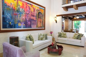 A spacious living room with a large abstract painting, white sofas, and a coffee table with decorative items. - Espectacular La Casita Cartagena (Cartagena)