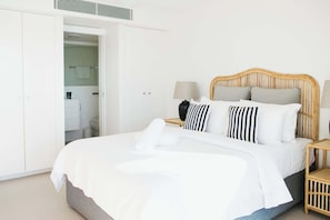 A bedroom with a bed, bedside tables, a wardrobe, and a bathroom visible through an open door.