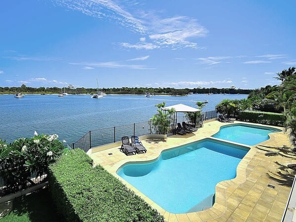 A swimming pool with lounge chairs and a view of the sea.