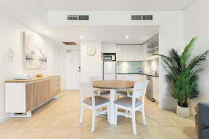 A modern kitchen with white cabinets, a microwave, and a refrigerator.