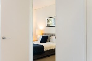 A hotel room with a bed, a nightstand, a lamp, and a framed picture on the wall.