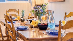 A dining table set with plates, glasses, a vase with flowers, and food items. - Mountain Cabin w/ Fireplace, Balcony & Easy Ski Access Bear Americana (Truckee)